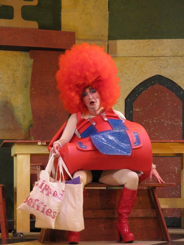 Actor Richard Conlon plays the part of an ugly sister in Cinderella. He is dressed in a huge red afro wig and red giant handbag costume designed by Alison Brown Costume Designer.