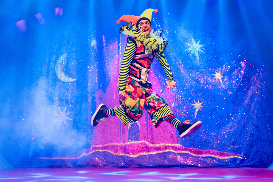 Actor Robert Jack leaps into the air in a colourful patterned jester's costume designed by Alison Brown Costume Designer.